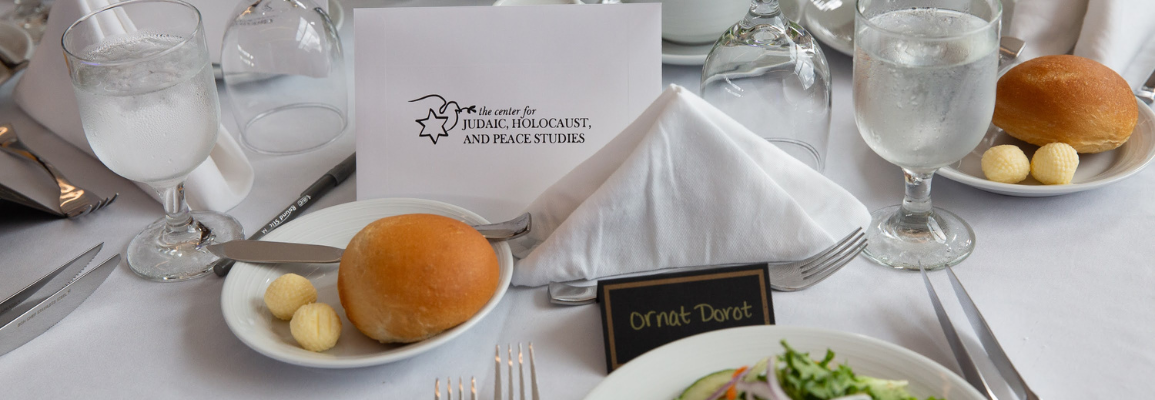 A table is set with food and a Center for Judaic, Holocaust and Peace Studies card.